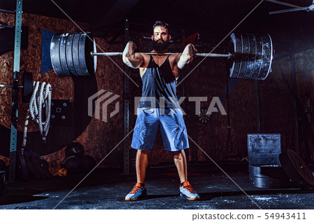 Muscular fitness man doing deadlift a barbell over his head in modern fitness center. Functional Muscular fitness man doing deadlift a barbell over his head in modern fitness center. Functional 54943411