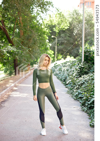 Young slim woman with a sporty body, long blond hair, dressed in a sports top and leggings, prepares Young slim woman with a sporty body, long blond hair, dressed in a sports top and leggings, prepares 54943573