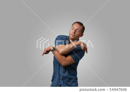 A man in a shirt shows with his hands on your text or your advertisement on a gray background 54947606