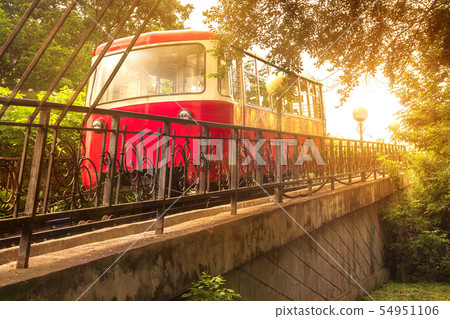 The Red Car of the Funicular rises in the bright sunlight of an evening sunset in the capital of the 54951106