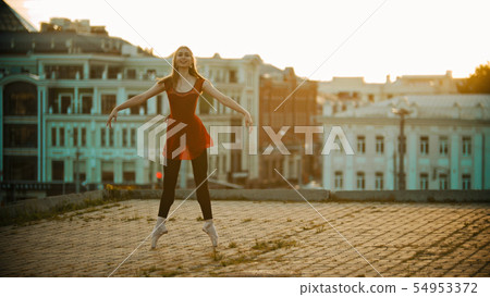 Young smiling woman ballerina training on the roof - standing on her tiptoes Young smiling woman ballerina training on the roof - standing on her tiptoes 54953372