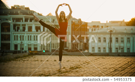 Young woman ballerina training on the roof - standing on her tiptoe in the pointe shoes and 54953375
