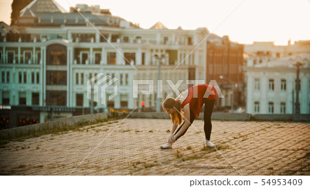 Young woman ballerina on the roof - training her stretching 54953409