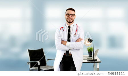 Handsome doctor standing in hospital office. 54955111