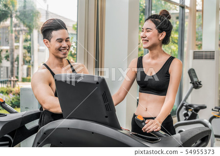 Sporty runner running on treadmill in fitness gym. 54955373