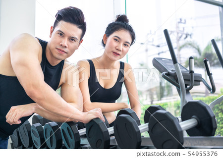 Healthy man and woman doing weight training in gym Healthy man and woman doing weight training in gym 54955376