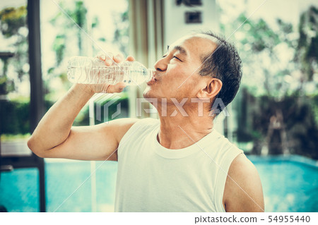 Senior man drink mineral water in fitness center. Senior man drink mineral water in fitness center. 54955440