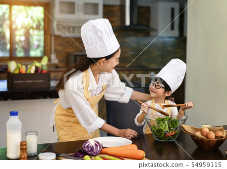 Mom teaching kid boy cooking healthy salad. Mom teaching kid boy cooking healthy salad. 54959115