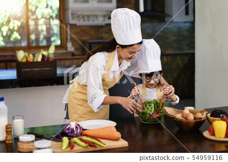 Mom teaching kid boy cooking healthy salad. 54959116