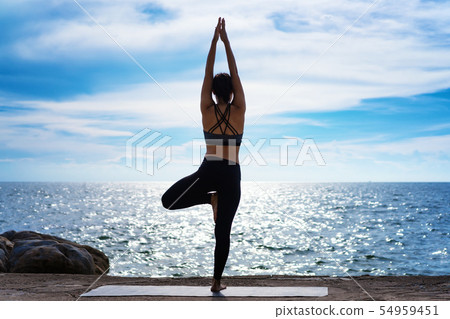 Portrait of young woman practicing yoga at the sea Portrait of young woman practicing yoga at the sea 54959451