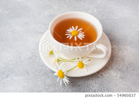 cup of herbal tea with chamomile flowers on grey  54960837