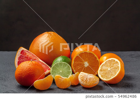 group of citrus fruits - tangerines, lemons, limes, oranges, grapefruits on the surface of a gray 54962486