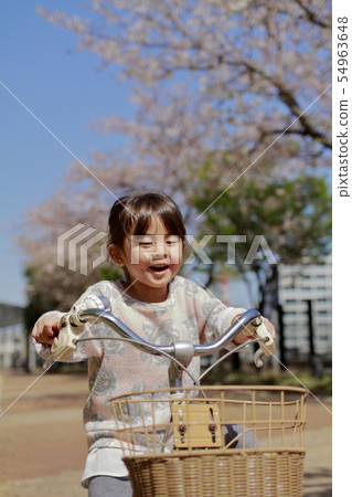 Toddler (4-year-old) riding a bicycle under the cherry blossoms Toddler (4-year-old) riding a bicycle under the cherry blossoms 54963648