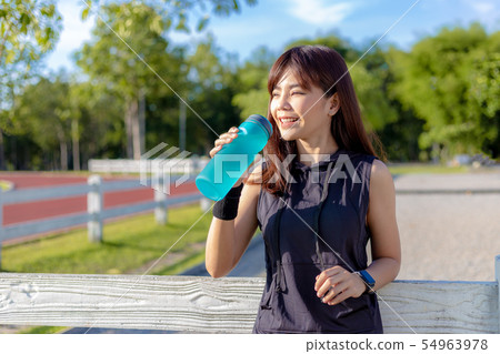 Beautiful happy young Asian woman drinking her 54963978