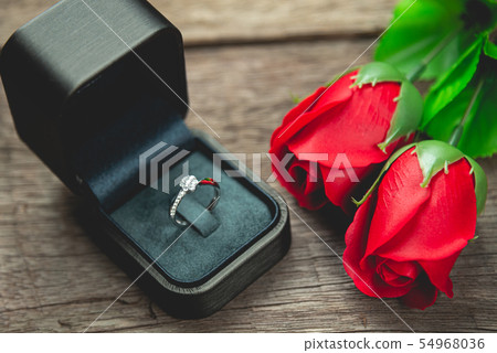 wedding ring and red rose flowers on wood table wedding ring and red rose flowers on wood table 54968036