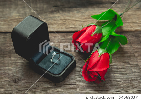 wedding ring and red rose flowers on wood table wedding ring and red rose flowers on wood table 54968037