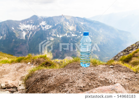 Clear water in a plastic bottle stands on a stone Clear water in a plastic bottle stands on a stone 54968183
