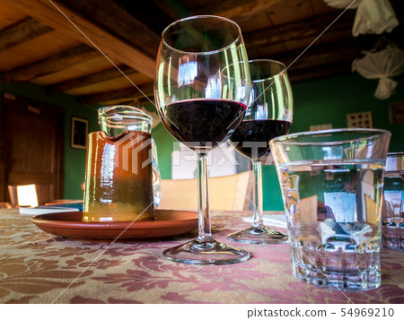 Glass of red wine on a table in rustic restaurant. Glass of red wine on a table in rustic restaurant. 54969210