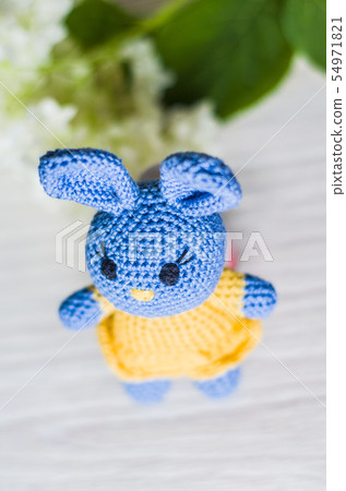 Crocheted hare of blue in yellow dress. 54971821