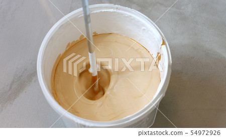 Process of mixing white paint with a color tinge in the bucket. Process of mixing white paint with a color tinge in the bucket. 54972926