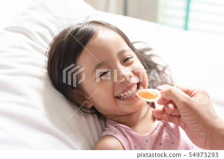 Happy asain girl taking medicine syrup from her 54973293