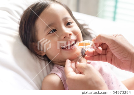 Happy asain girl taking medicine syrup from her 54973294