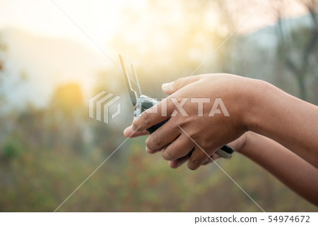 hands with remote controller of drone outside. 54974672