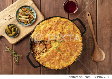 Shepherd's pie with pickles and red wine, overhead shot on a dark rustic wooden background Shepherd's pie with pickles and red wine, overhead shot on a dark rustic wooden background 54982707