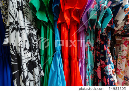 Cocktail dress. Clothing on hanger at the modern shop boutique. Bright multi-colored fabrics Cocktail dress. Clothing on hanger at the modern shop boutique. Bright multi-colored fabrics 54983805