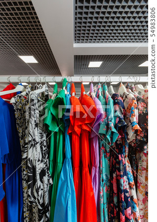 Cocktail dress. Clothing on hanger at the modern shop boutique. Bright multi-colored fabrics Cocktail dress. Clothing on hanger at the modern shop boutique. Bright multi-colored fabrics 54983806