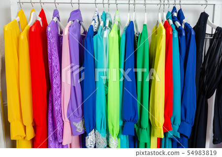 Cocktail dress. Clothing on hanger at the modern shop boutique. Bright multi-colored fabrics Cocktail dress. Clothing on hanger at the modern shop boutique. Bright multi-colored fabrics 54983819