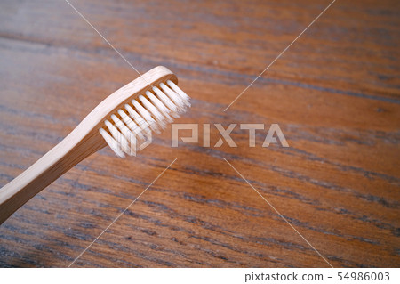 Close up of wooden bamboo toothbrush on wood table Close up of wooden bamboo toothbrush on wood table 54986003