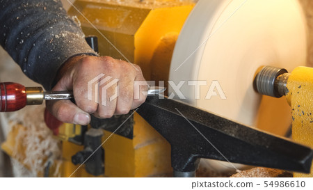 Craftsman works with workpiece in workshop. 54986610