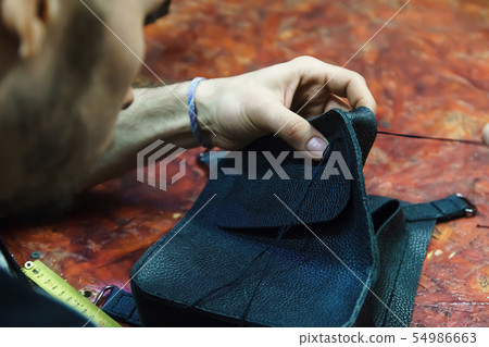 Tanner sews leather item. Tanner sews leather item. 54986663