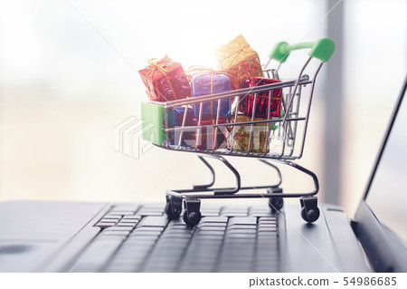 Online shopping concept. Shopping cart, small gift boxes, laptop on the desk 54986685