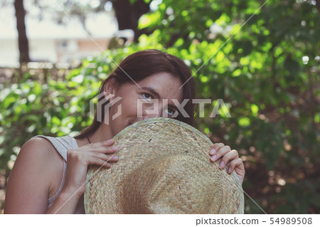 The woman covered her face with her hat. The woman covered her face with her hat. 54989508
