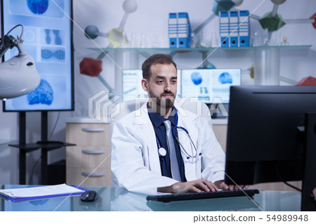 Portrait of young doctor in white coat working in his hospital office Portrait of young doctor in white coat working in his hospital office 54989948