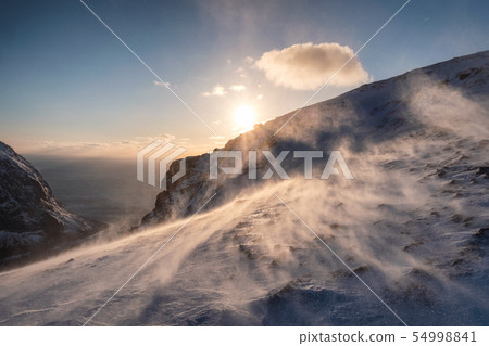 Sunset on snowy hill in blizzard at sunset Sunset on snowy hill in blizzard at sunset 54998841