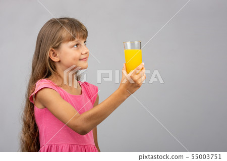 A girl holds a glass of juice in her hand and 55003751