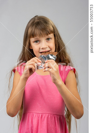 Eight-year-old girl eats chocolate bar Eight-year-old girl eats chocolate bar 55003753
