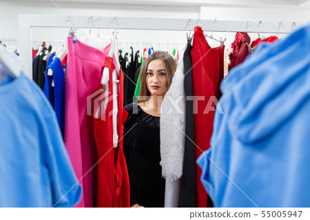 Happy young woman choosing clothes in mall or clothing store. 55005947