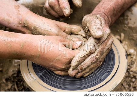 two pairs of hands create a clay product on a 55006536