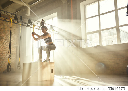 Working out. Side view of beautiful athletic woman in sportswear training legs at gym. Working out. Side view of beautiful athletic woman in sportswear training legs at gym. 55016375