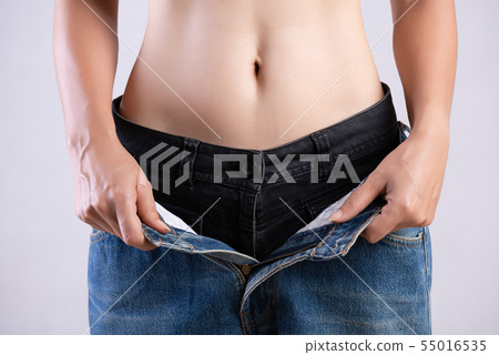 Young slim woman in oversized blue jeans. Young slim woman in oversized blue jeans. 55016535