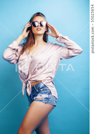 young pretty girl in sunglasses posing happy smiling on blue background, lifestyle people on summer 55025654