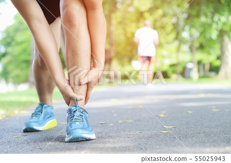 Runner touching painful twisted or broken ankle. Runner touching painful twisted or broken ankle. 55025943
