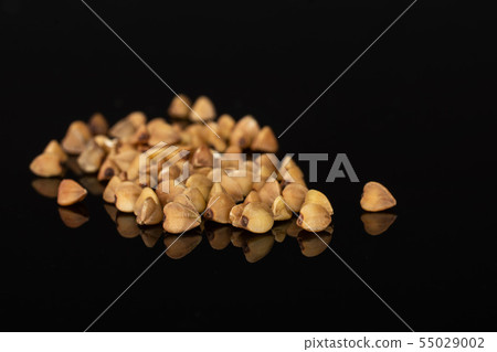 Raw buckwheat grain isolated on black glass Raw buckwheat grain isolated on black glass 55029002