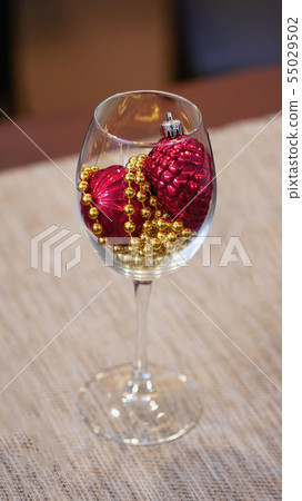 Christmas home decoration, bright red balls and golden garland in wineglass Christmas home decoration, bright red balls and golden garland in wineglass 55029502