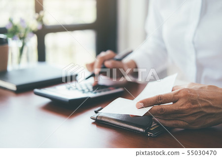 Woman with bills and calculator. Woman using 55030470