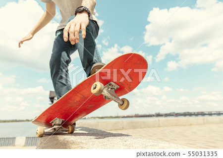 Skateboarder doing a trick at the city's street in sunny day Skateboarder doing a trick at the city's street in sunny day 55031335